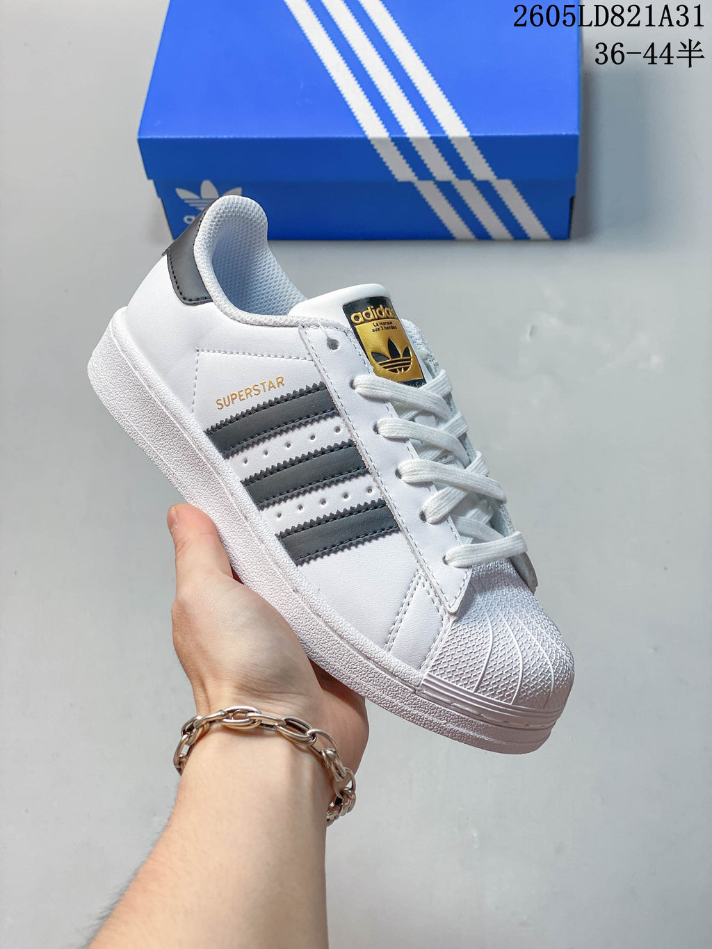 White Adidas Superstar sneaker with dark stripes, dark heel tab and shell toe.