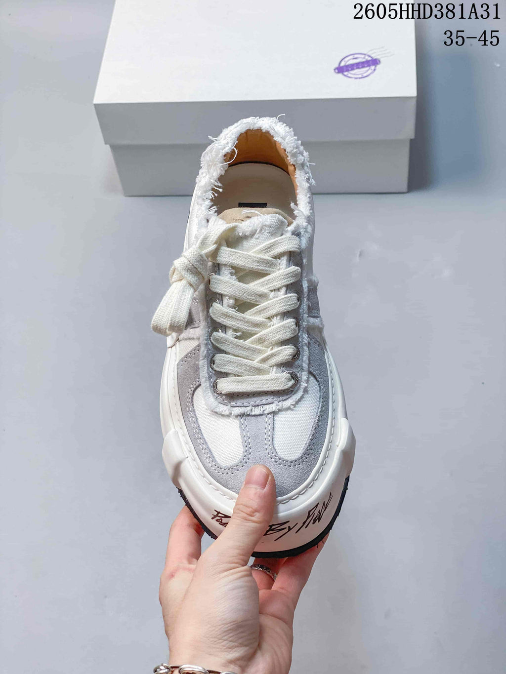 Front view of a white and gray xVESSEL low-top sneaker with lace-up fastening