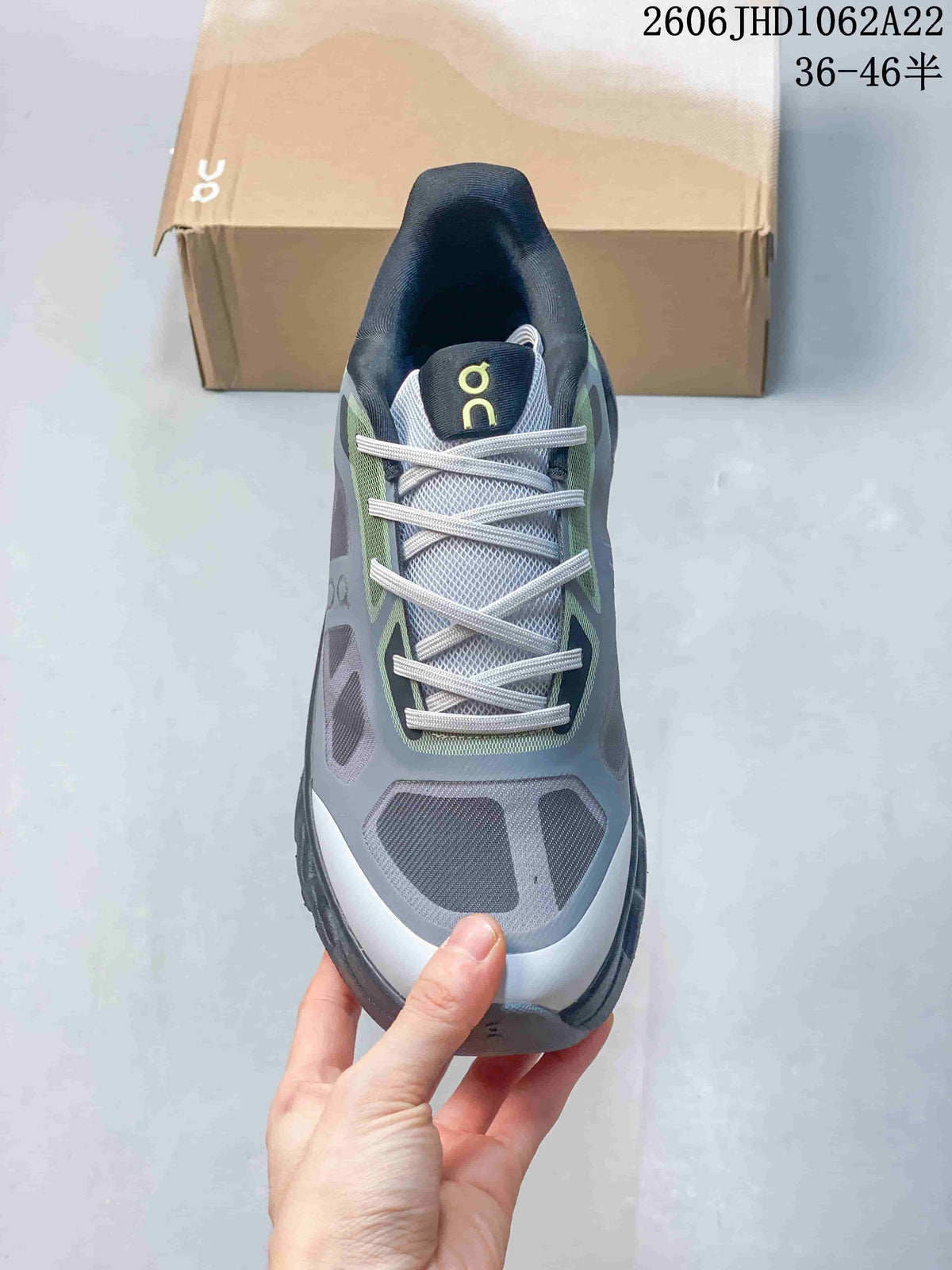 Top view of the lace-up upper and tongue on a gray and lime On sneaker.