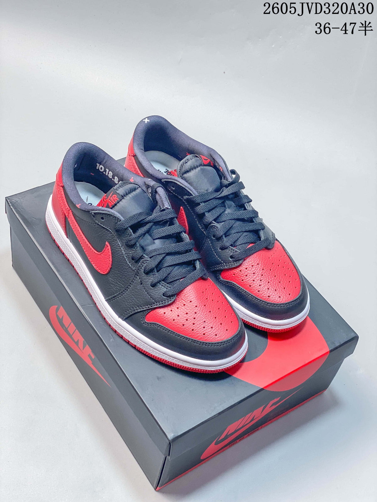Pair of red and dark grey Air Jordan 1 Low sneakers displayed on a shoebox