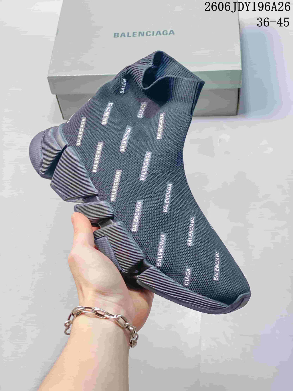 Close view of a dark gray sock-style sneaker with repeated Balenciaga branding and a segmented sole.