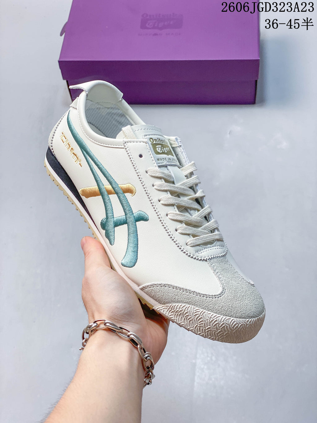 Close view of an ivory Mexico 66 NM sneaker with teal embroidered side stripes and a textured toe bumper.