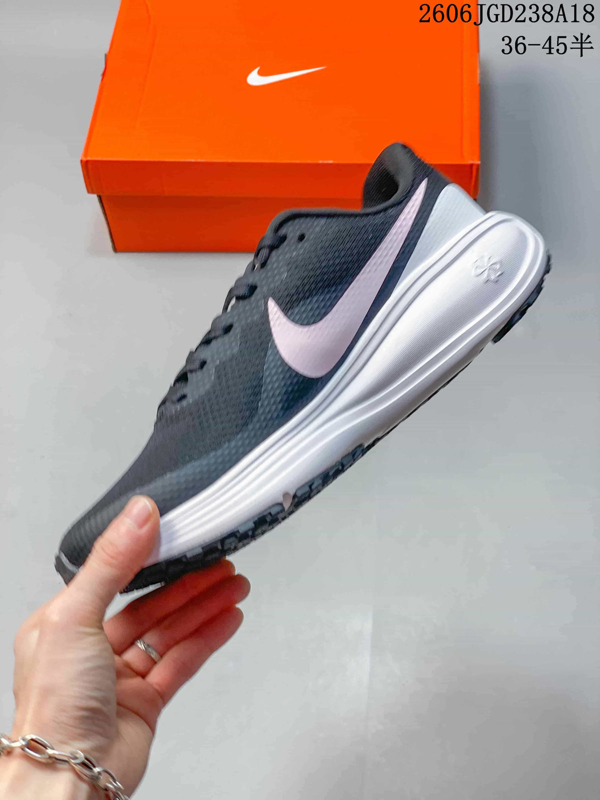 Side view of the charcoal running shoe with pale pink Swoosh and white midsole