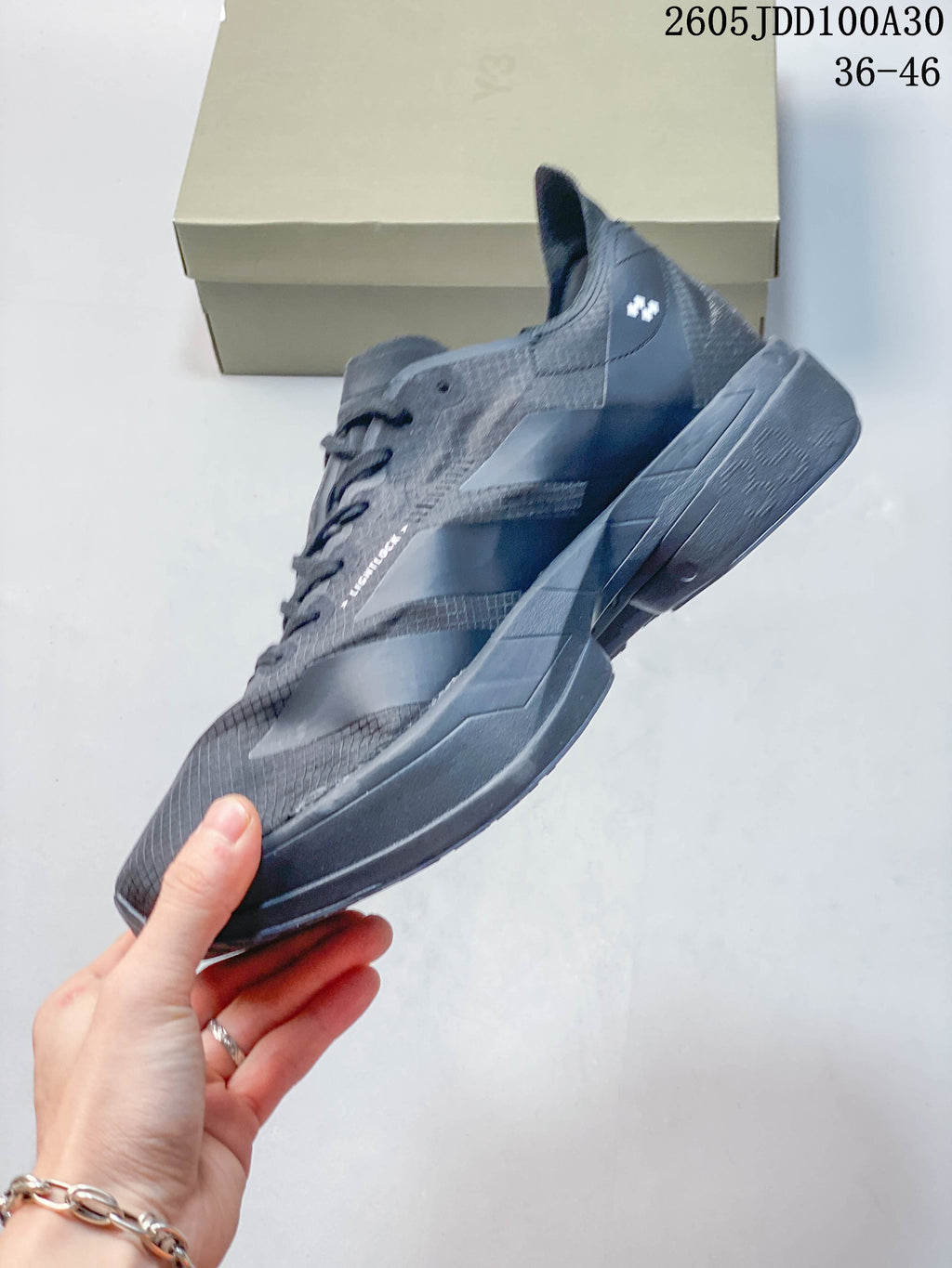 Side profile of a gray running shoe with white stripes and a sculpted sole