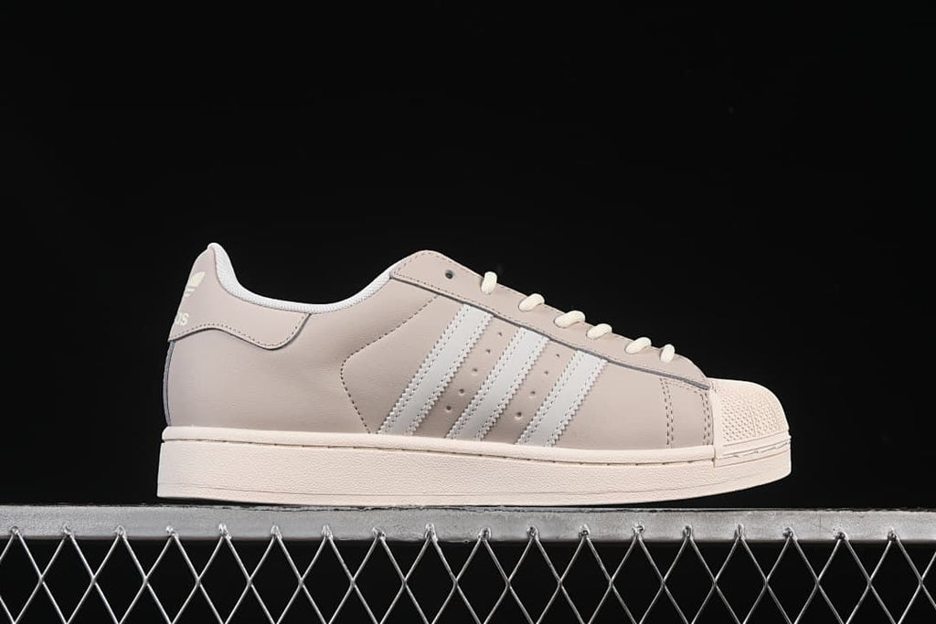 Side profile showing the beige upper, white stripes and off-white sole.