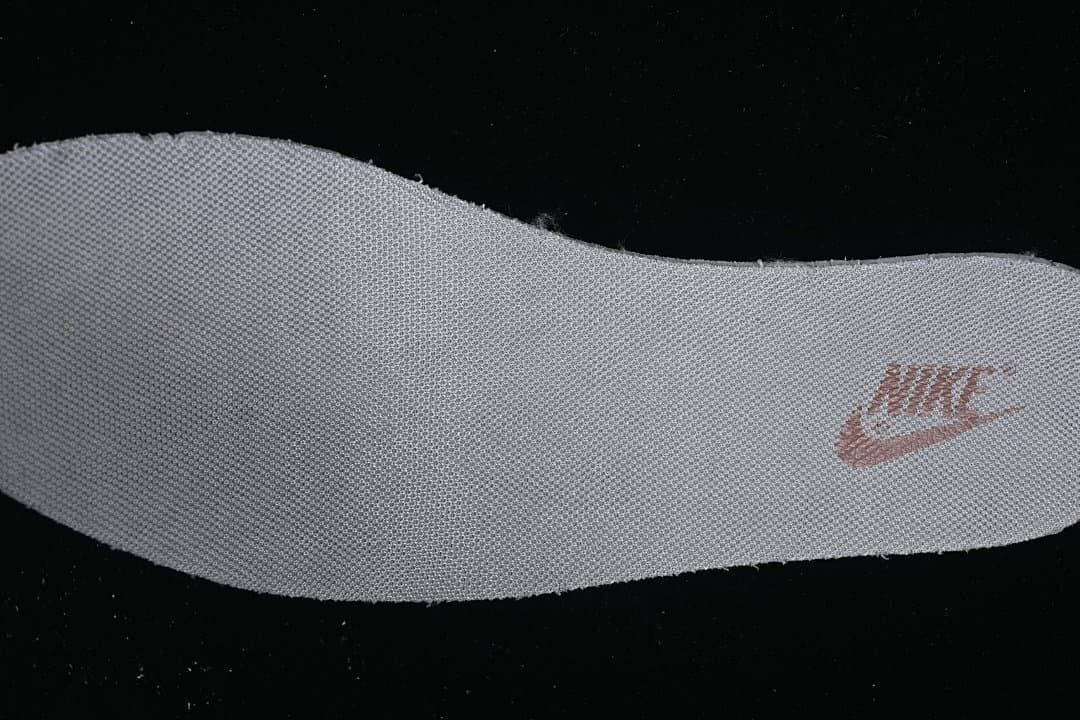 Close-up view of a textured white shoe component with a small printed logo.