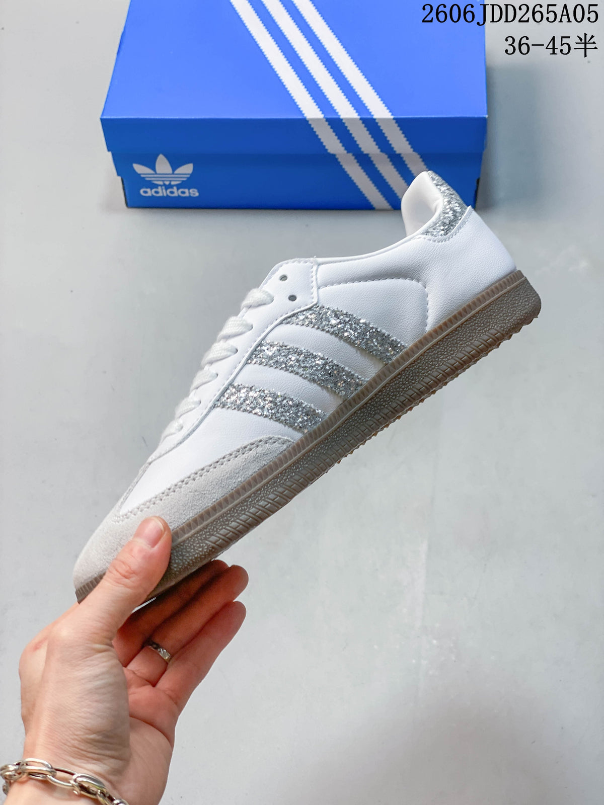 Side view showing the white Samba OG upper, silver-look stripes, gray overlays, and gum-colored outsole.