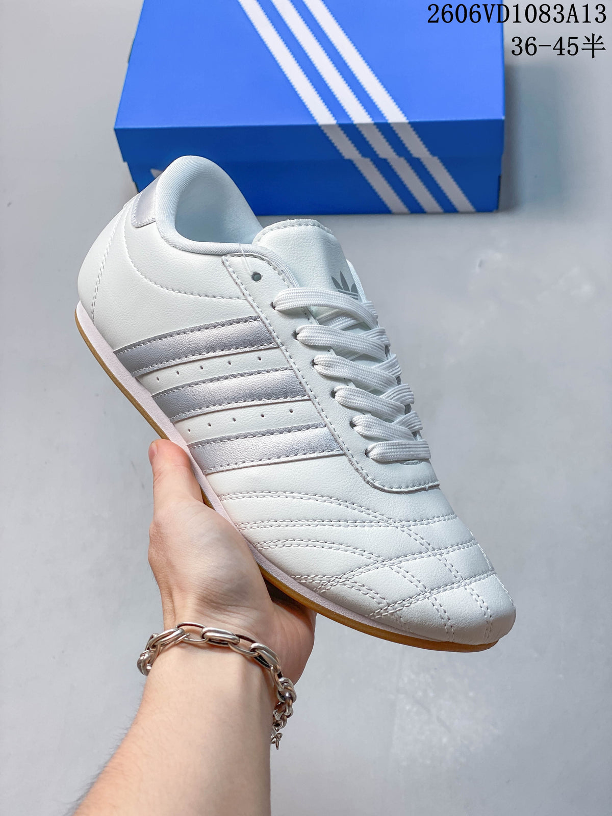Angled side view of a white lace-up sneaker with silver-tone stripes.