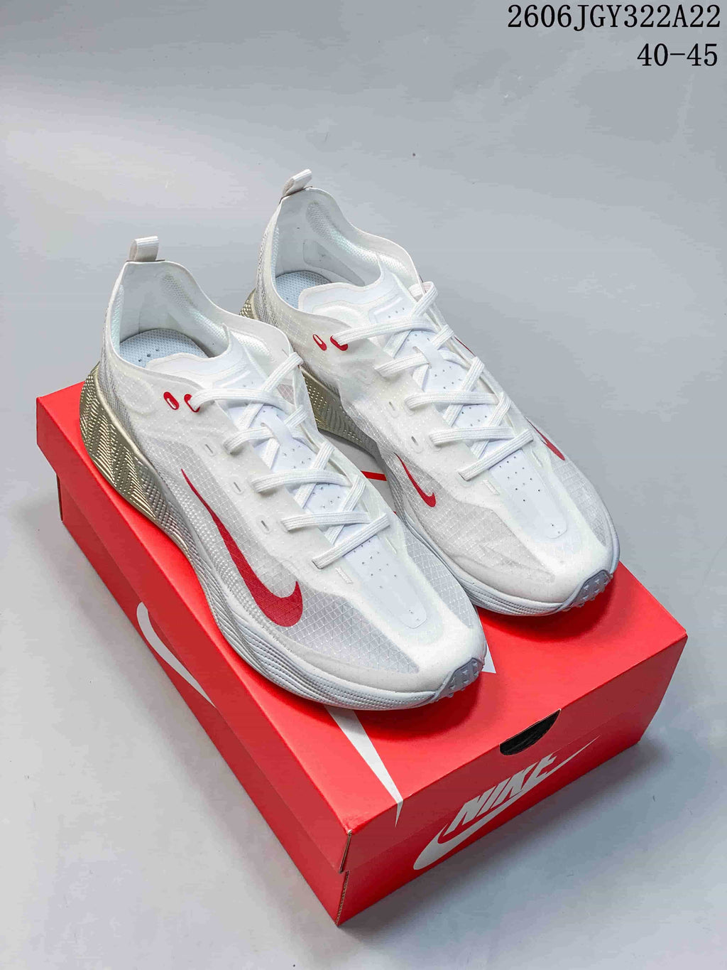 Pair of white Nike Ava X low-top shoes with red Swoosh accents, shown on a red shoebox.