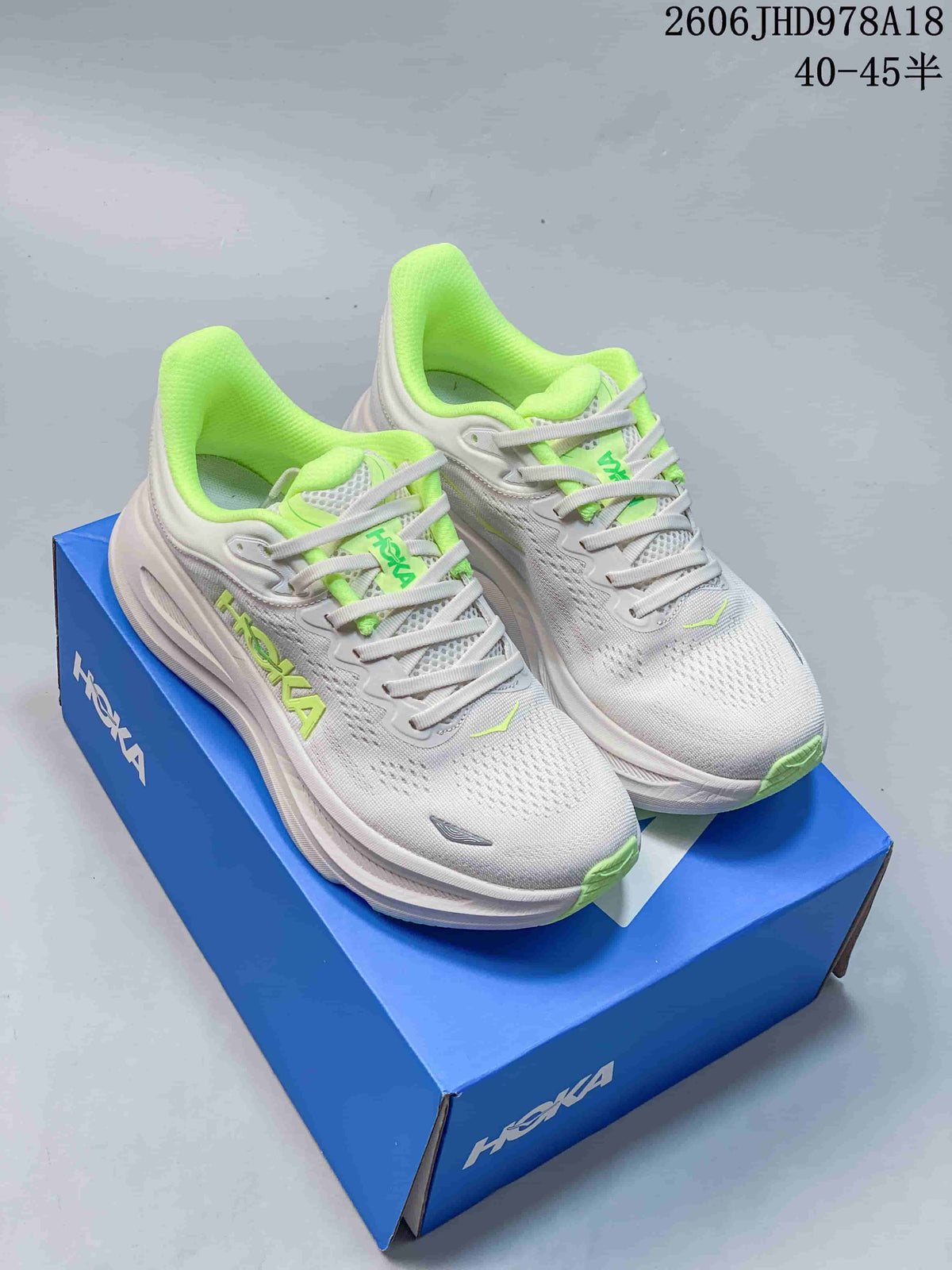 Pair of white HOKA Bondi 9 running shoes with neon-green accents on a blue shoe box