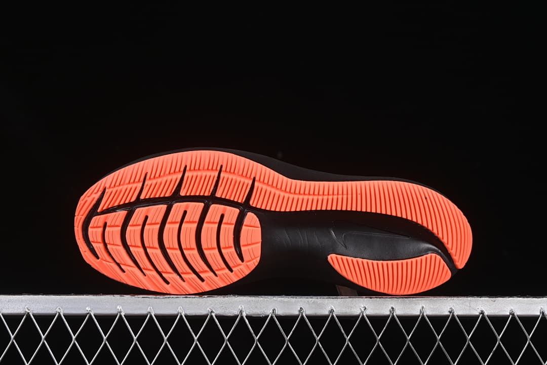 Underside of the shoe showing a coral-orange and black tread pattern.
