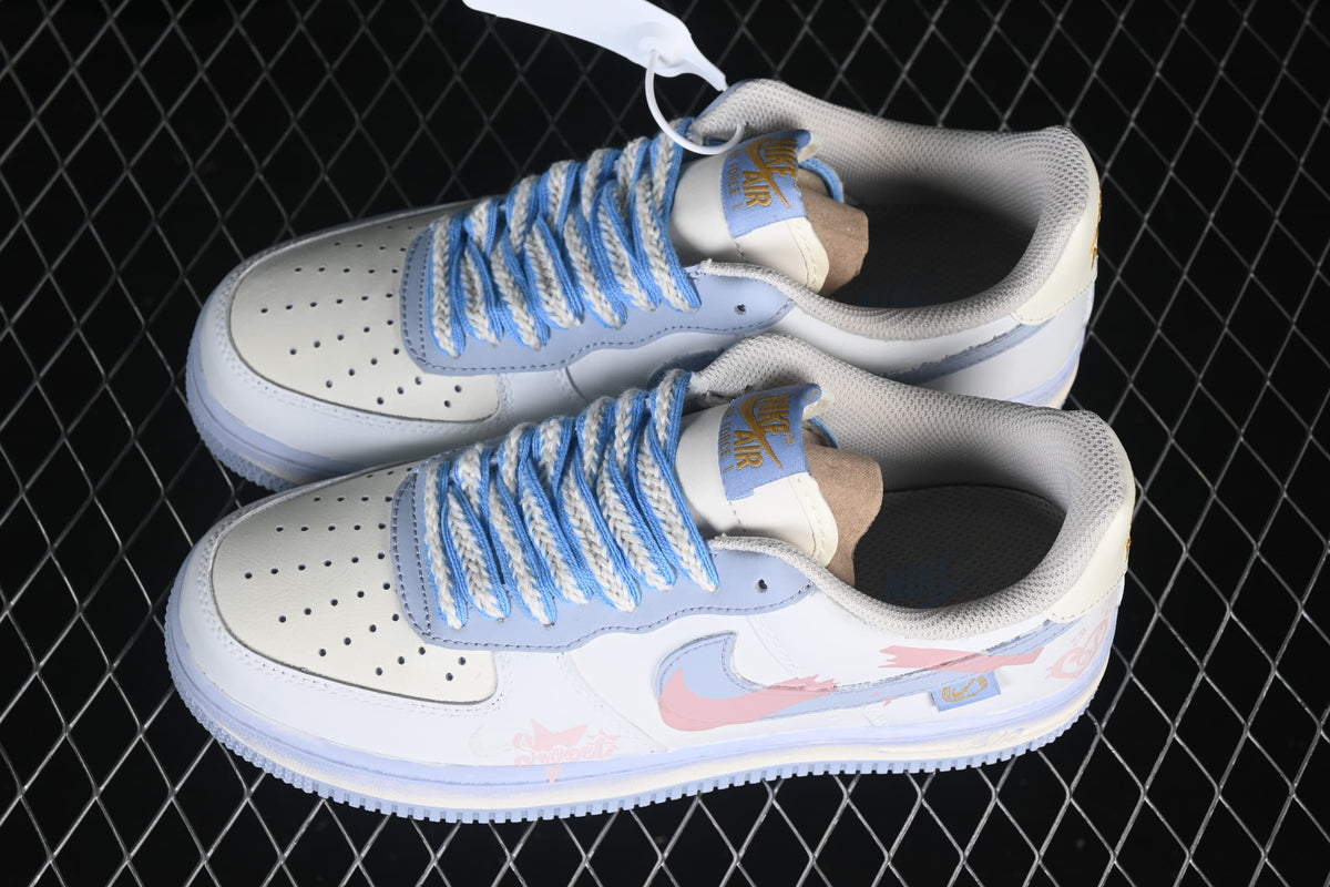Pair of white and pale blue Nike Air Force 1 '07 low-top sneakers with braided blue-and-cream laces and pink side graphics