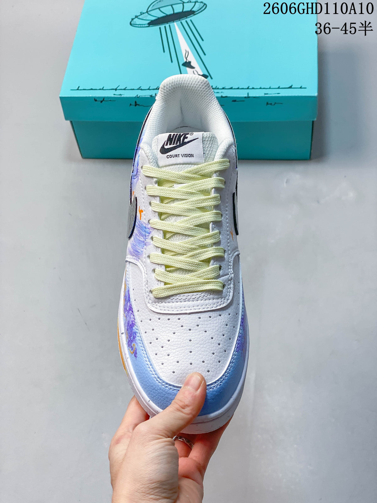 Top view of a white sneaker showing its perforated toe, pale yellow laces, and colorful side details.