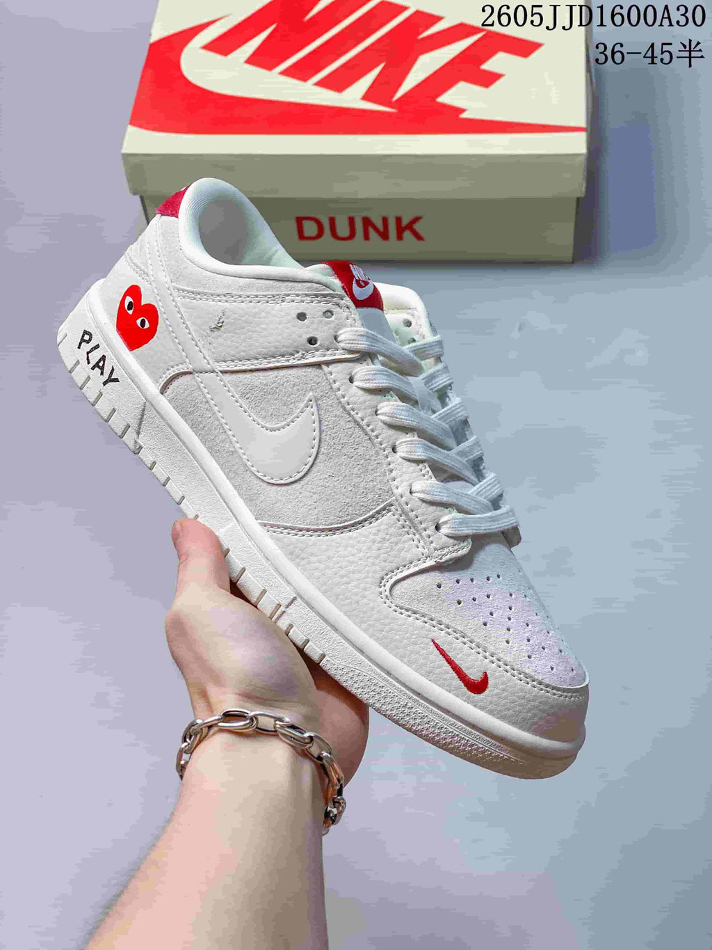 Side view of an off-white low-top sneaker with red heart graphic and PLAY lettering