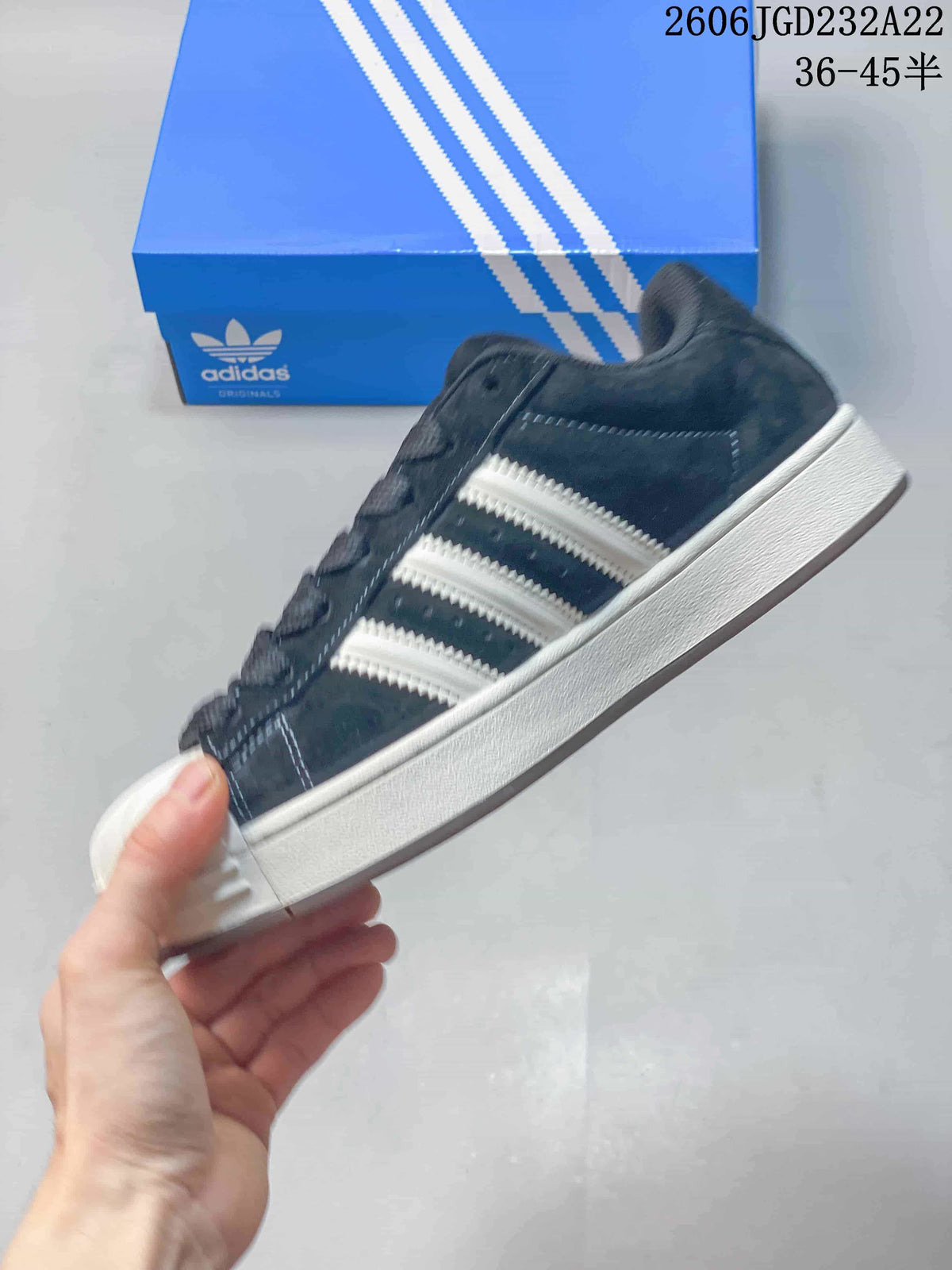 Side view of the dark low-top sneaker with contrasting stripes and a shell toe