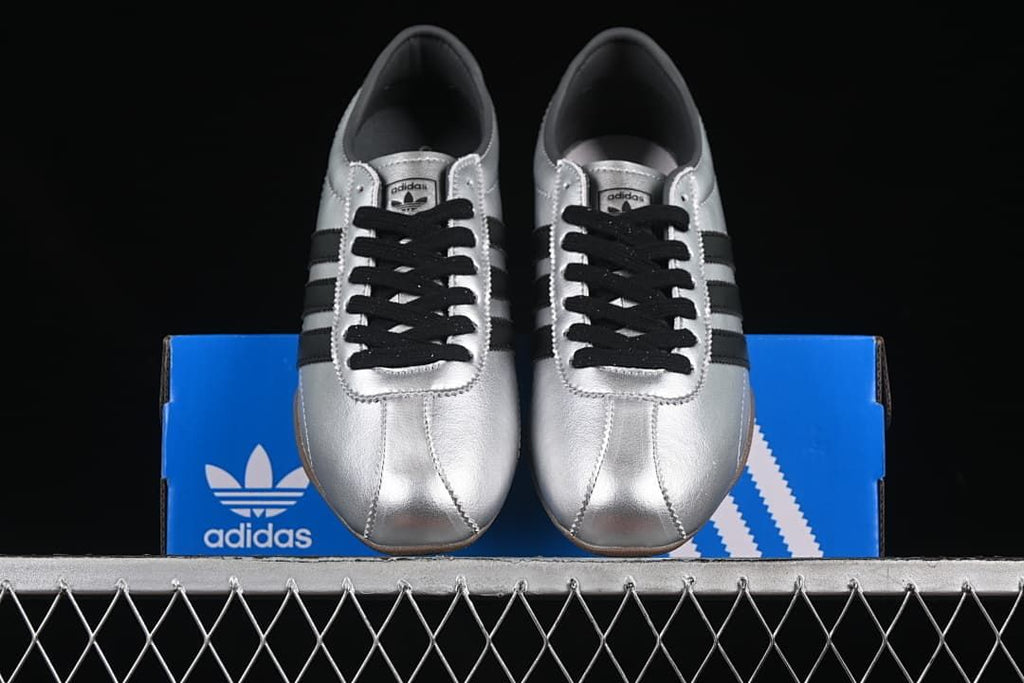 Front view of the silver sneakers displayed on a blue adidas box