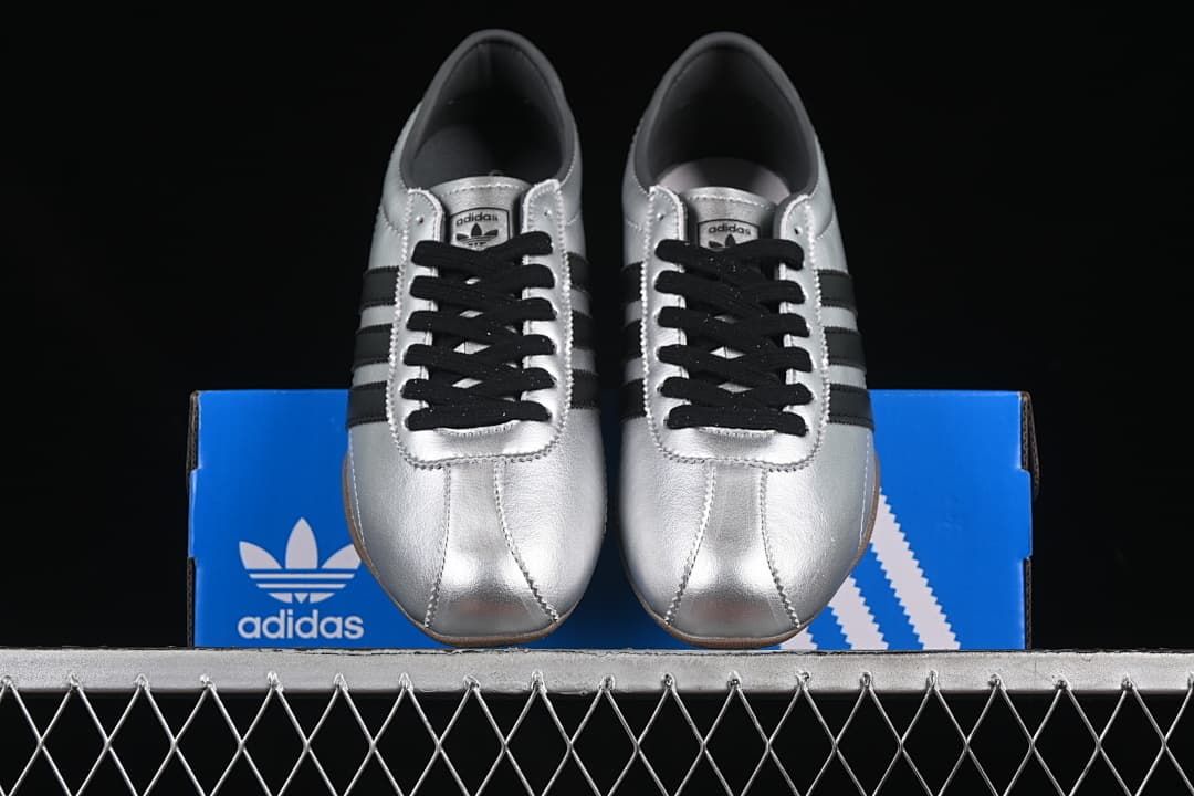 Front view of the silver sneakers displayed on a blue adidas box