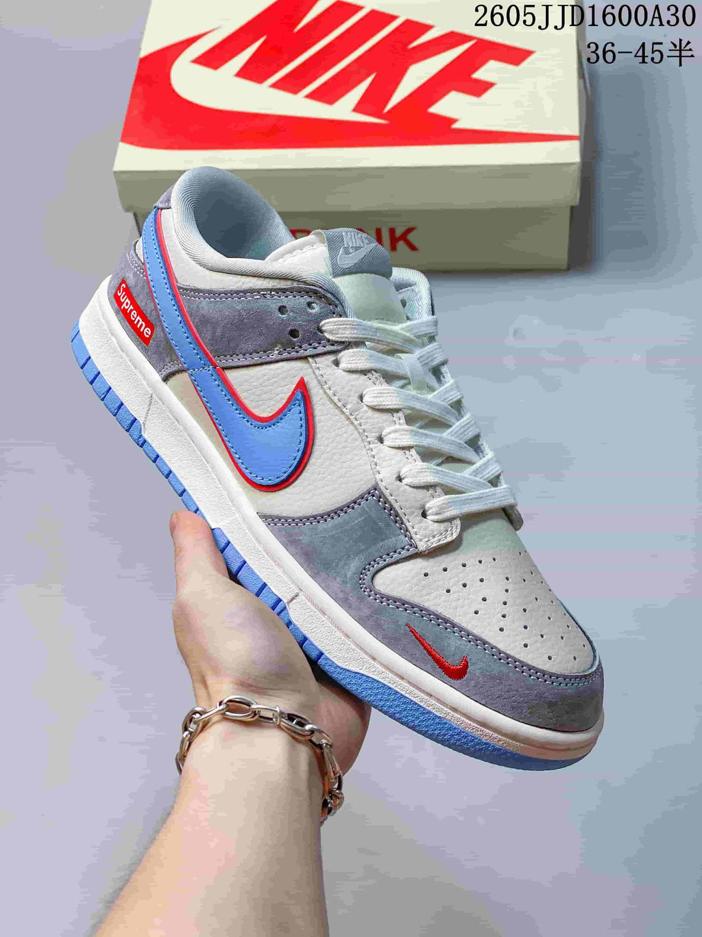 Close-up angled view of a grey Nike SB Dunk Low sneaker with blue and red accents