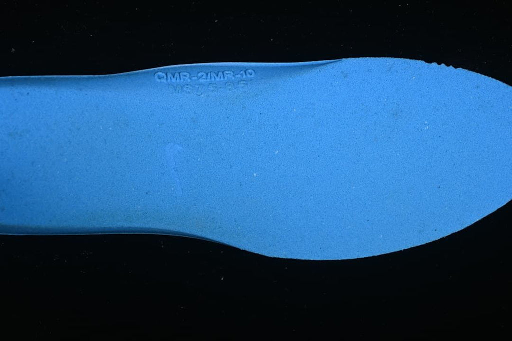 Close-up of a blue shoe insert with a faint embossed marking.