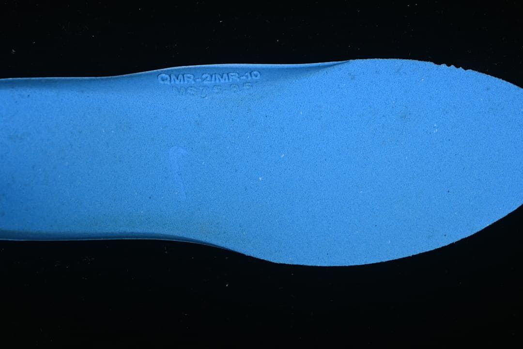 Close-up of a blue shoe insert with a faint embossed marking.