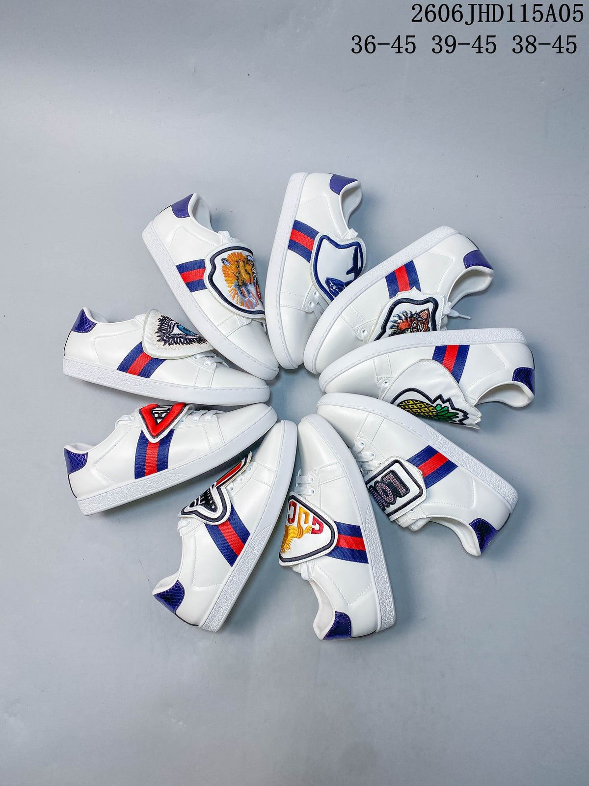 Group of white sneakers showing multiple embroidered tongue-flap designs and red-and-blue side stripes.