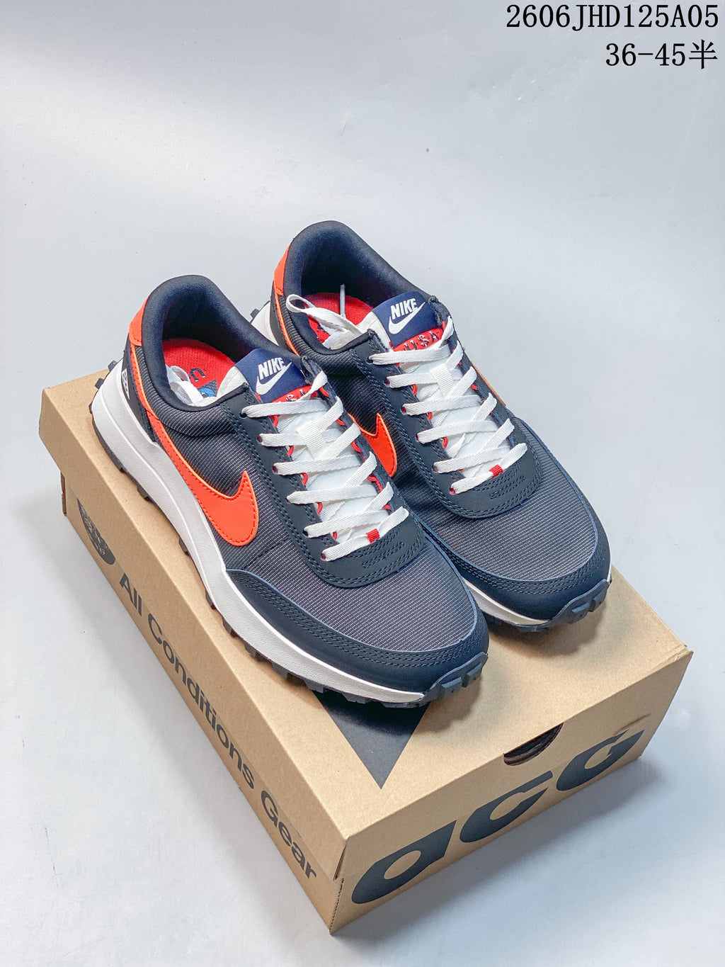 Nike ACG LDV sneakers in charcoal, navy, white, and orange displayed on a box