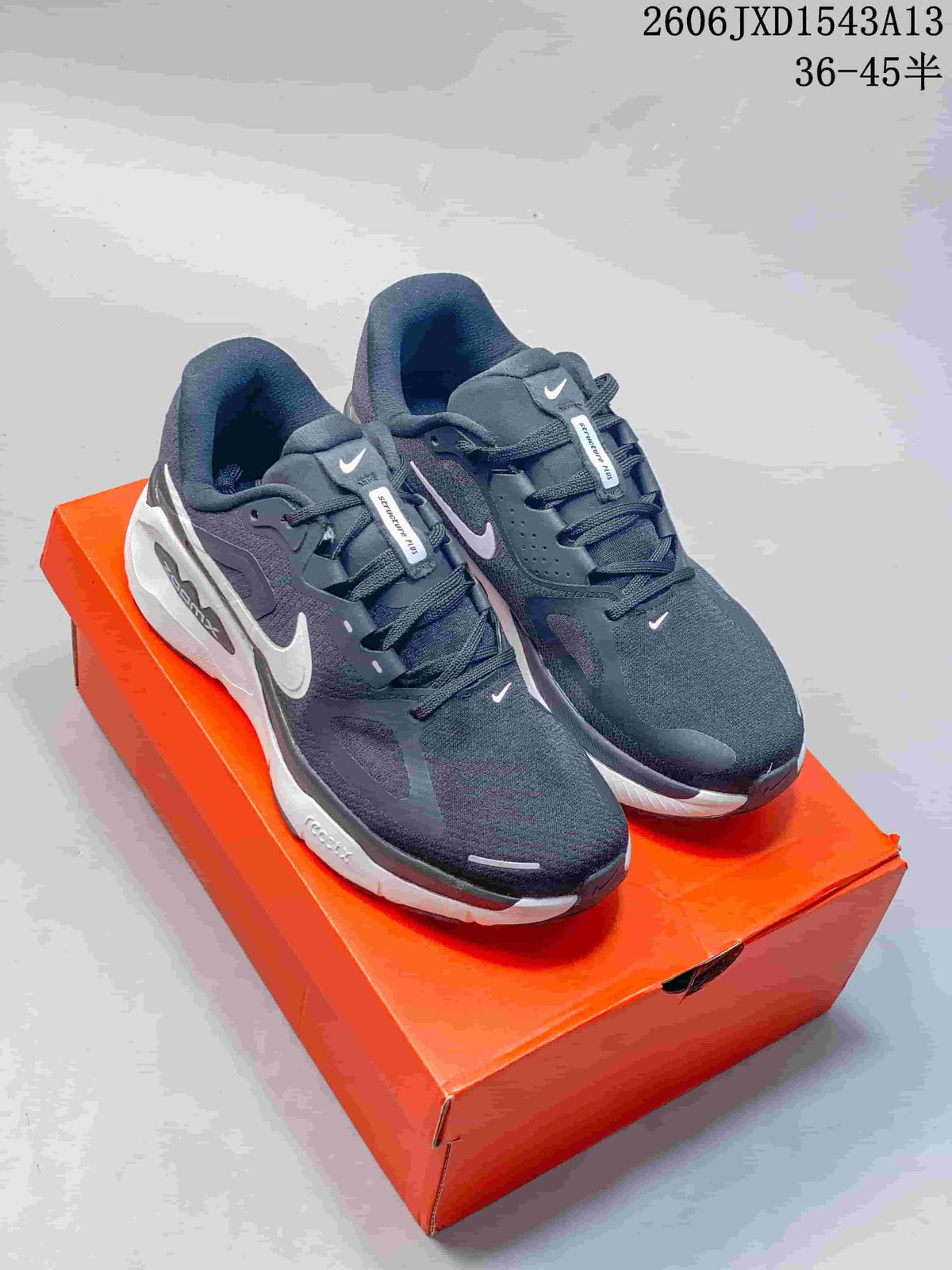Pair of charcoal and white Nike Structure Plus running shoes on an orange shoebox.