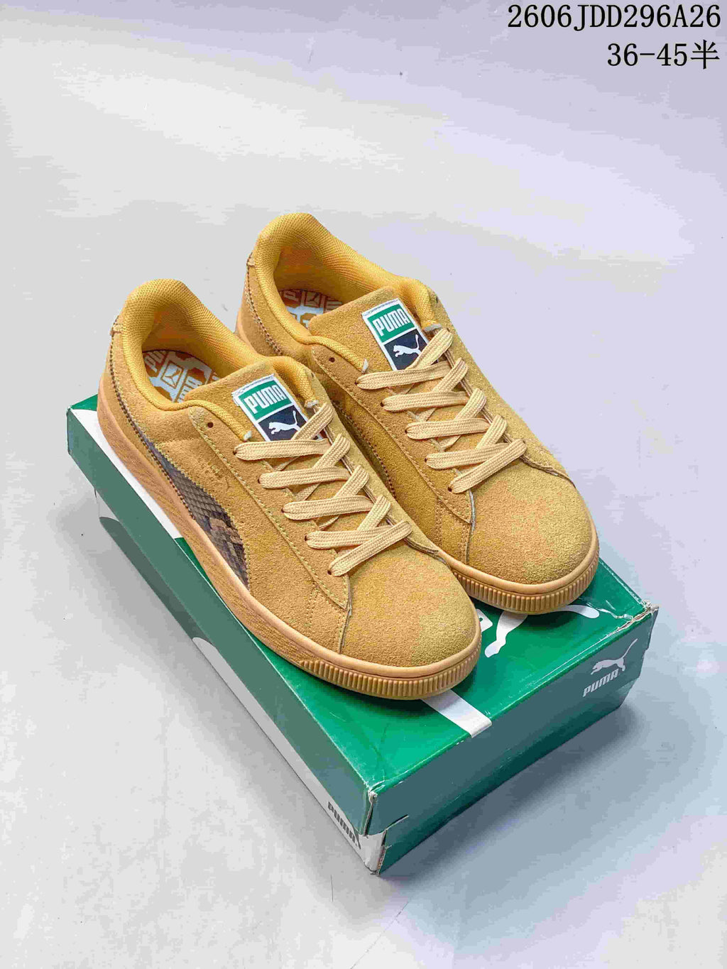 Pair of wheat-toned PUMA Suede Shed low-top sneakers displayed on a green shoe box