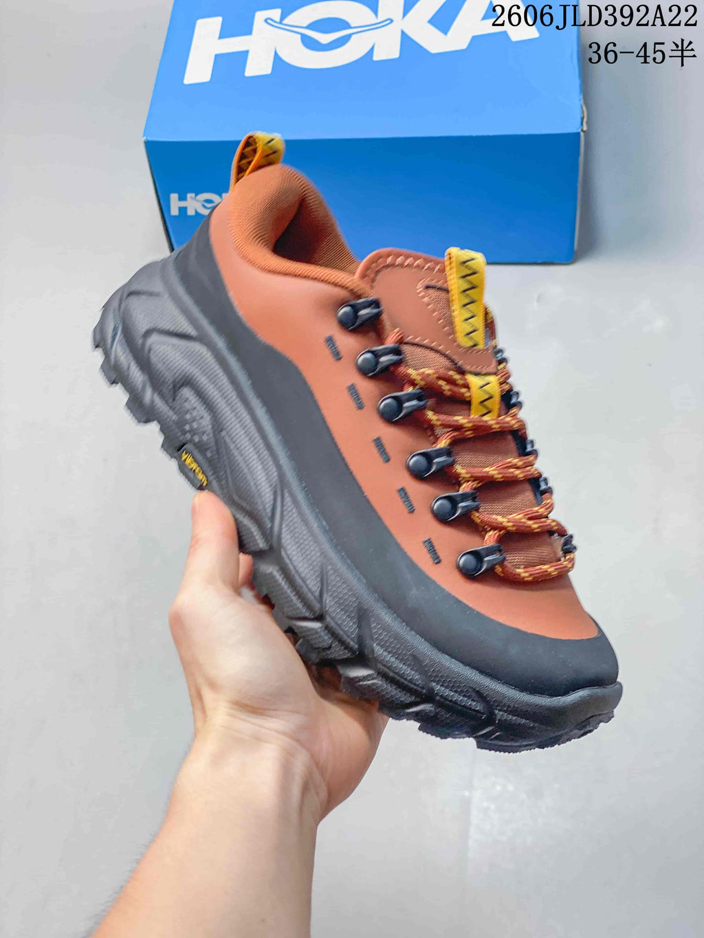 Side view of a rust orange and charcoal HOKA low-top sneaker with lace-up closure