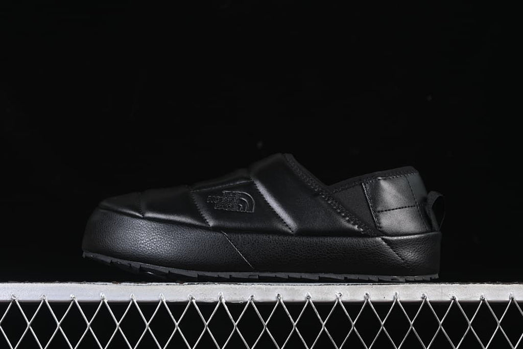 Side profile of a black mule with quilted upper and textured sole.