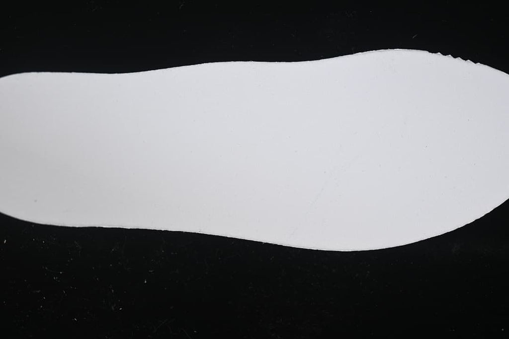 Plain white shoe-shaped insert photographed against a dark background.