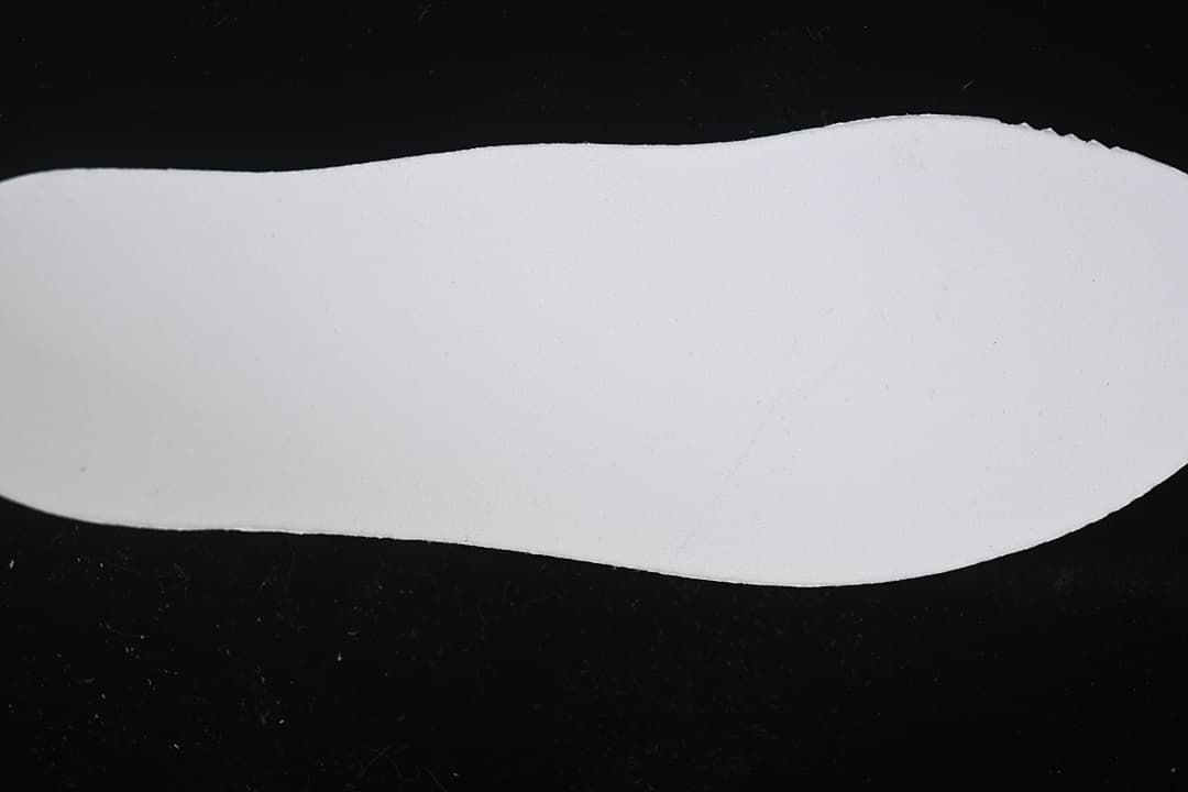 Plain white shoe-shaped insert photographed against a dark background.