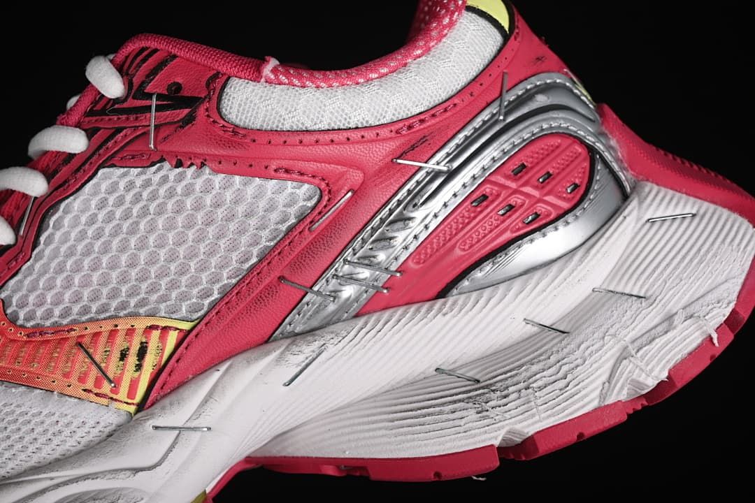 Close-up of layered pink and silver side details above the white midsole