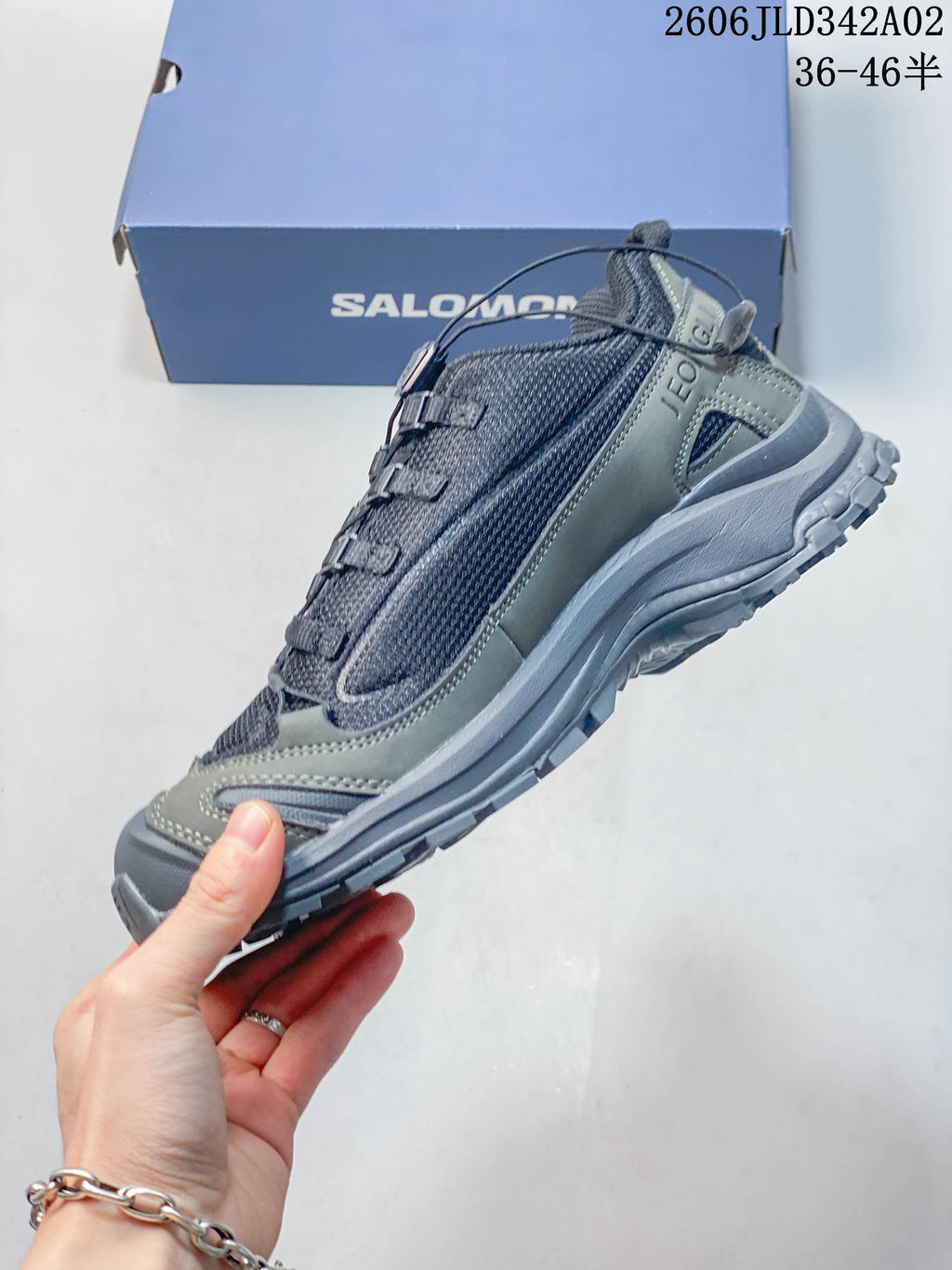 Side profile of a gray Salomon trail shoe with quick lacing and protective overlays.