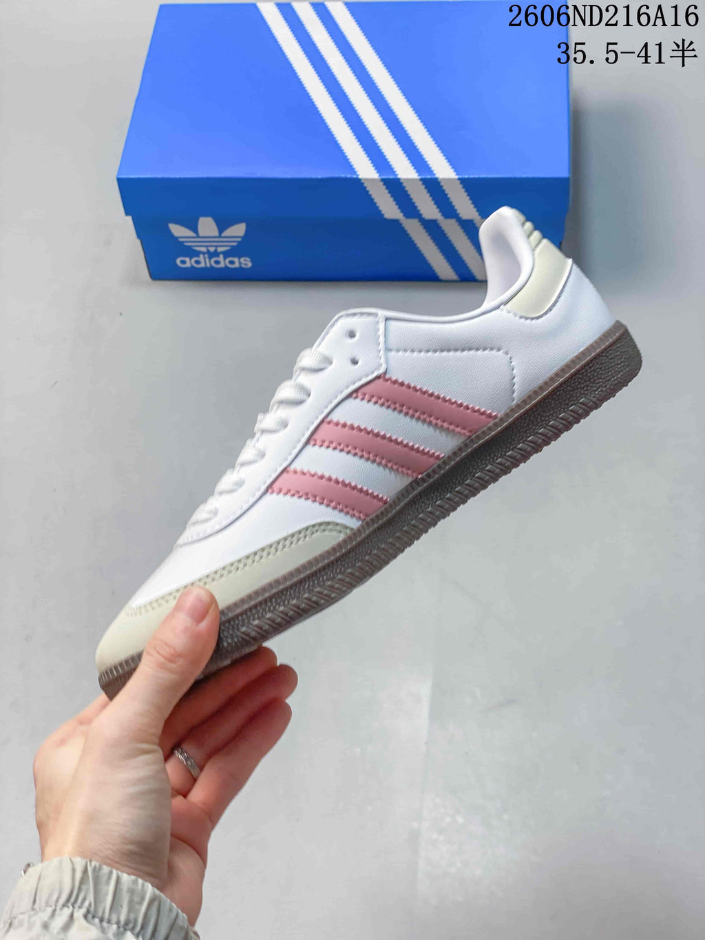 Side profile of a white low-top sneaker with pink stripes, pale neutral overlays, and a gum-toned outsole
