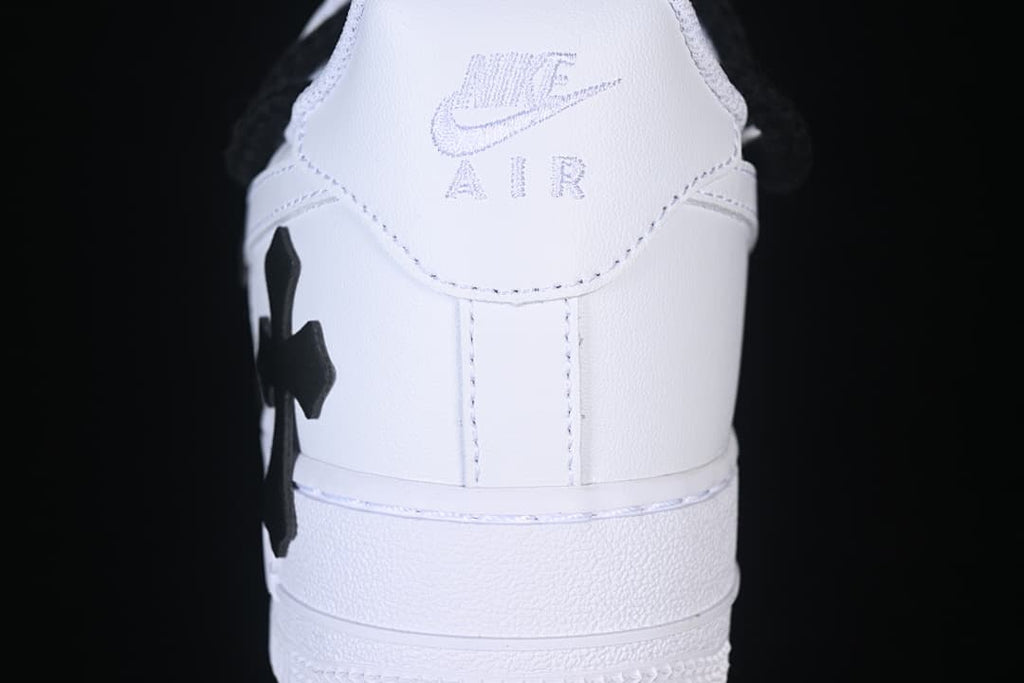 Rear view of the white sneaker with a black cross-shaped detail at the side.