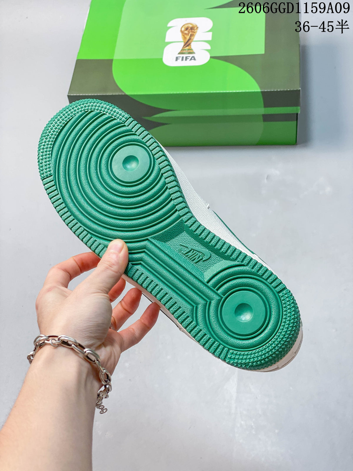 Green outsole of a white low-top sneaker beside a green shoe box