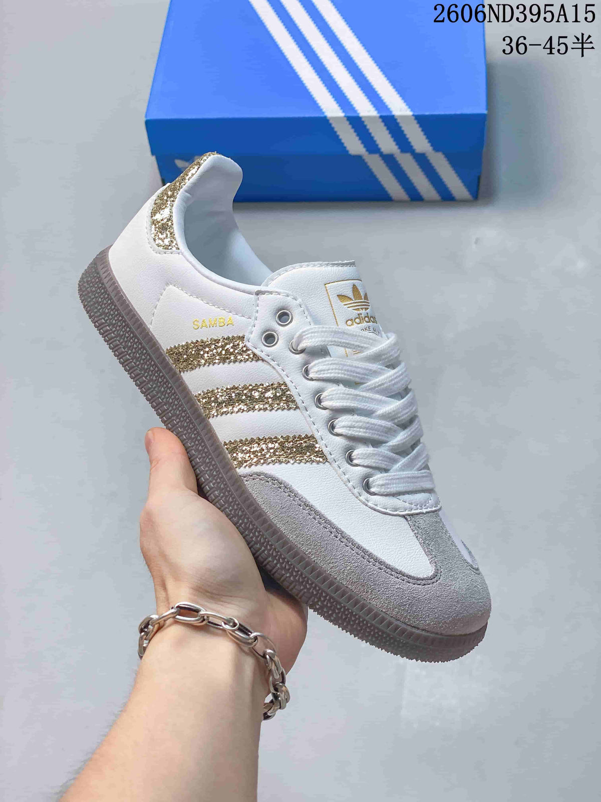 Side view of a white low-top sneaker with gold-tone glitter stripes and gray toe panels