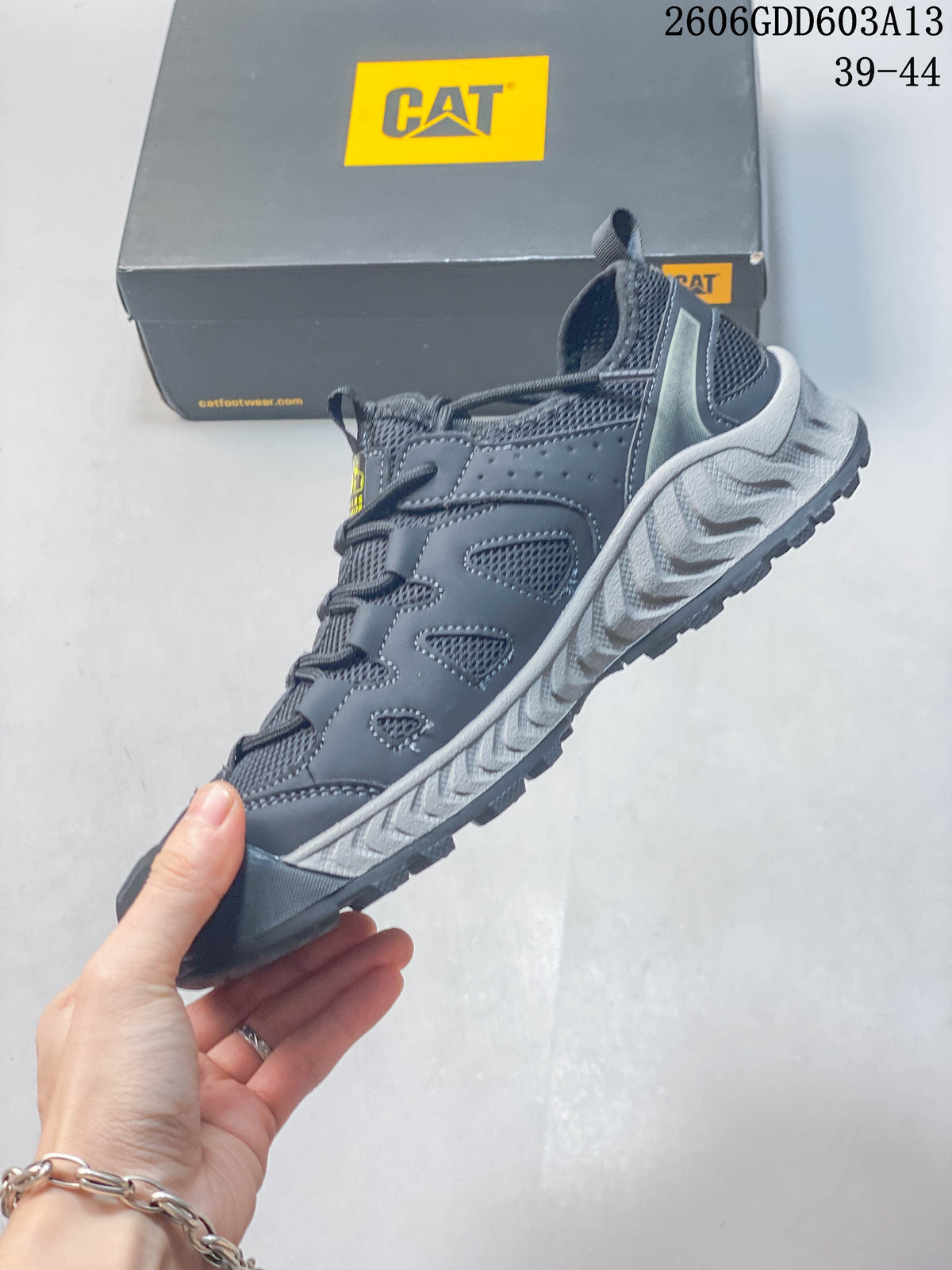 Side view of the dark gray CAT sneaker with mesh panels, lace-up fastening, and textured sole