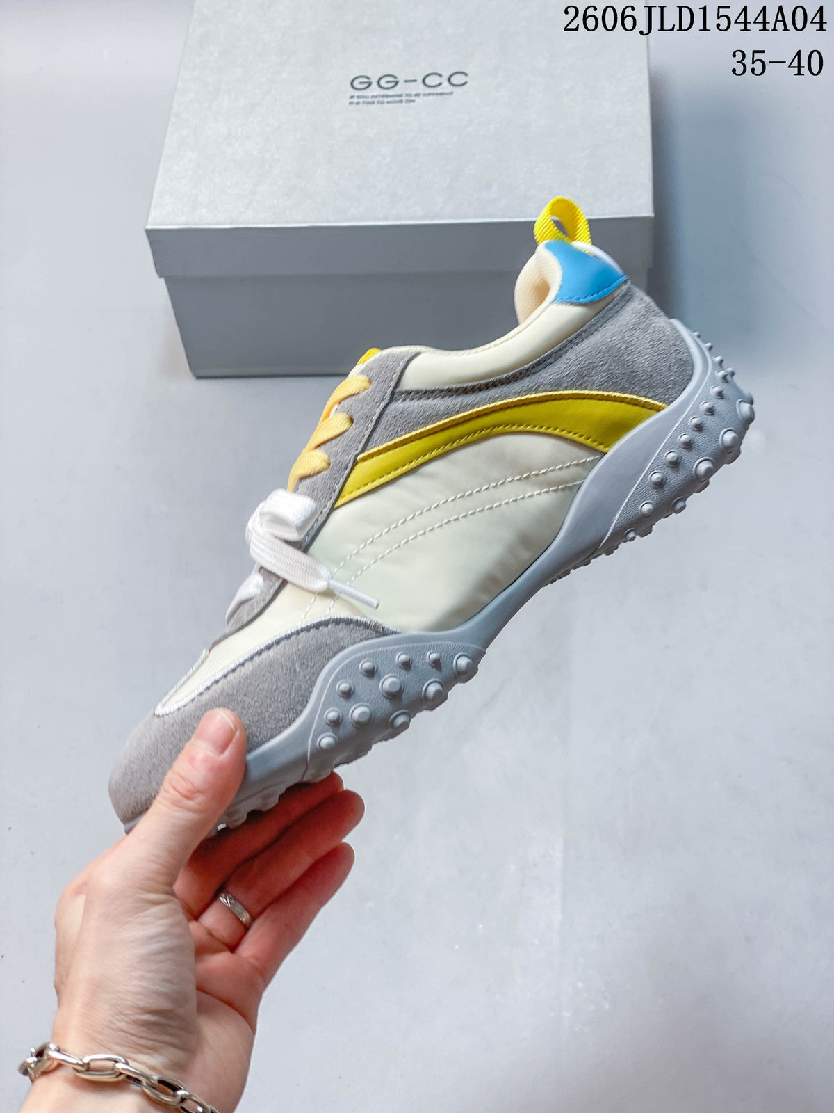 Side view of the low-top sneaker with cream panels, gray overlays, and a yellow accent stripe.