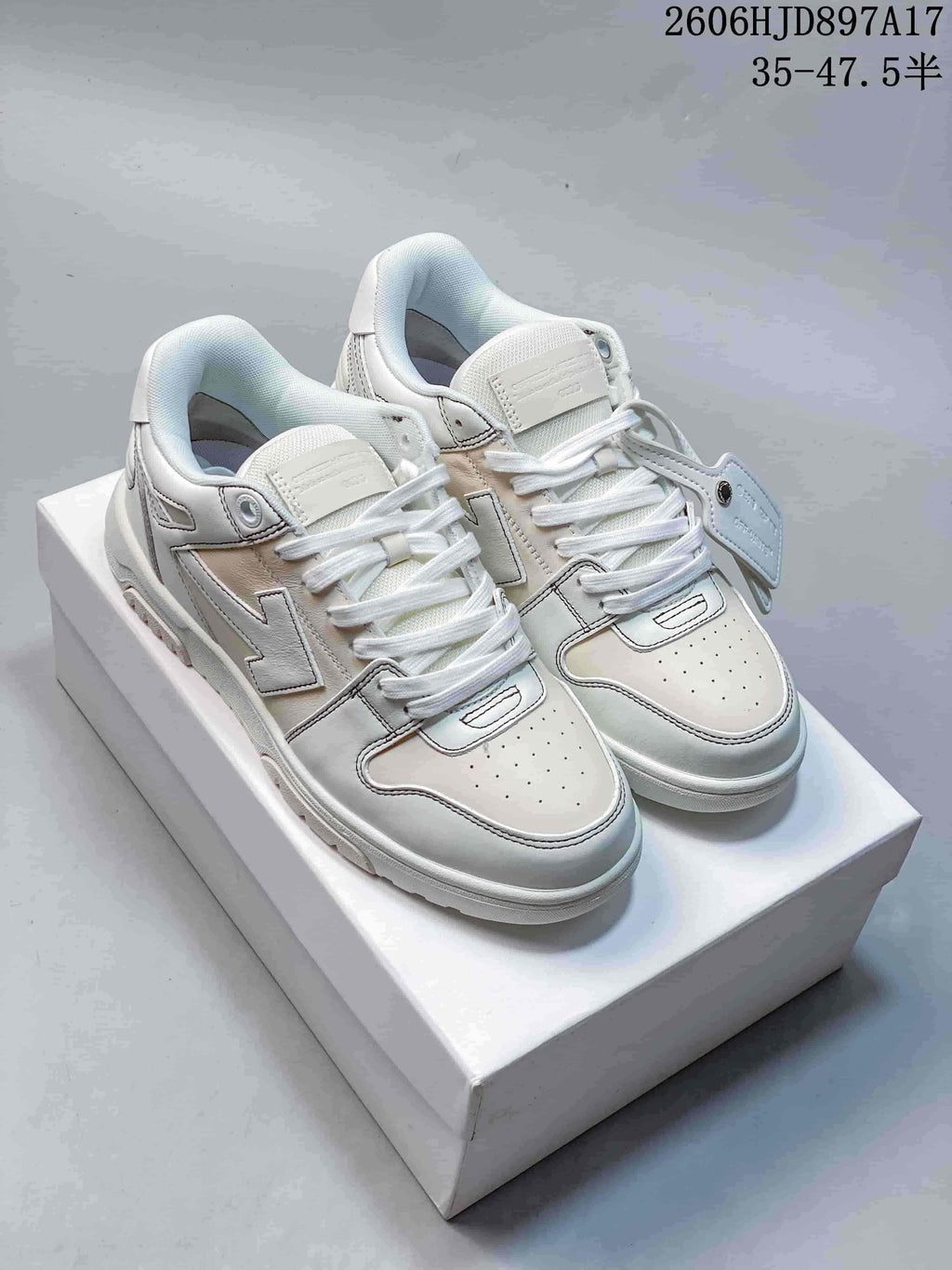 Pair of white low-top sneakers with lace-up fronts and arrow-shaped side details