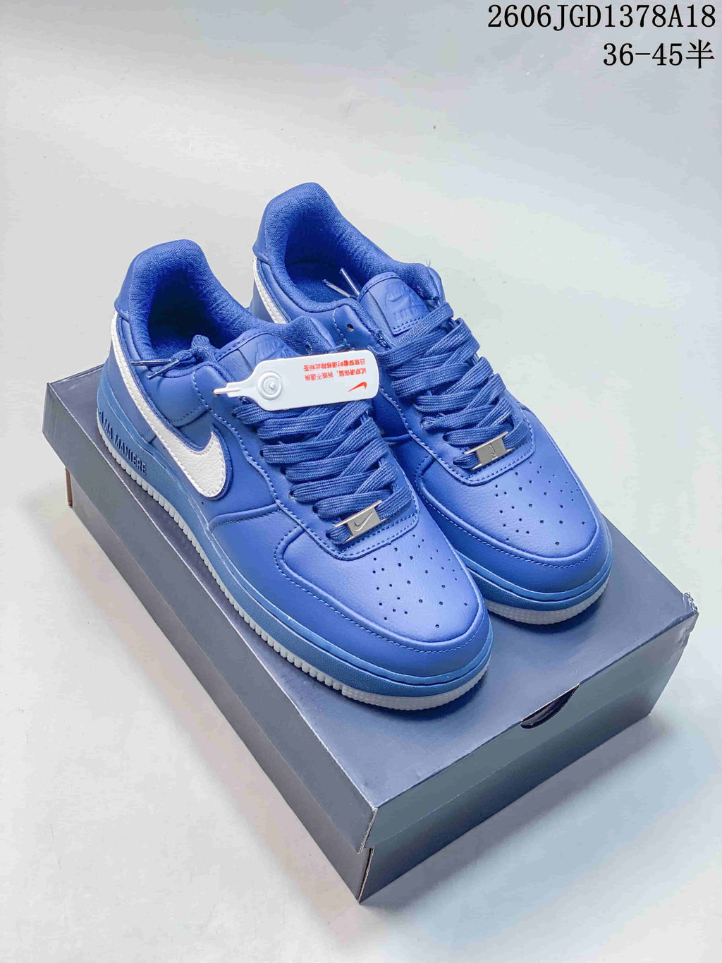 Pair of blue low-top sneakers with white side Swooshes on a shoe box