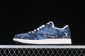 Side view of a dark blue patterned low-top sneaker with white graphics, white midsole, and dark outsole.