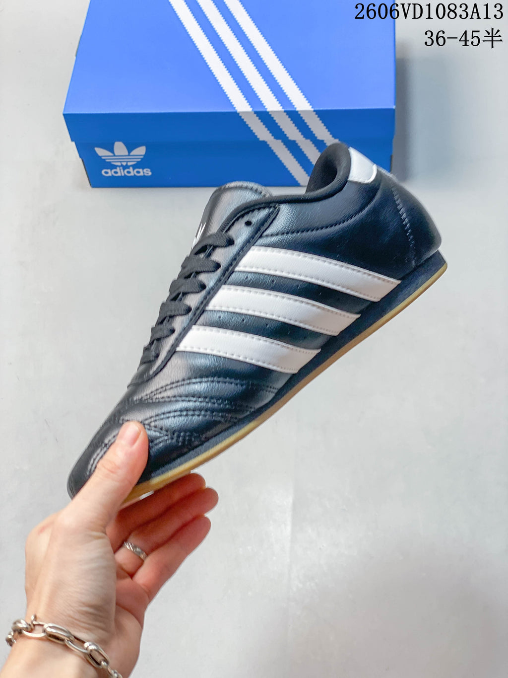 Side view of the navy Adidas Originals Taekwondo sneaker with white stripes and gum-colored outsole