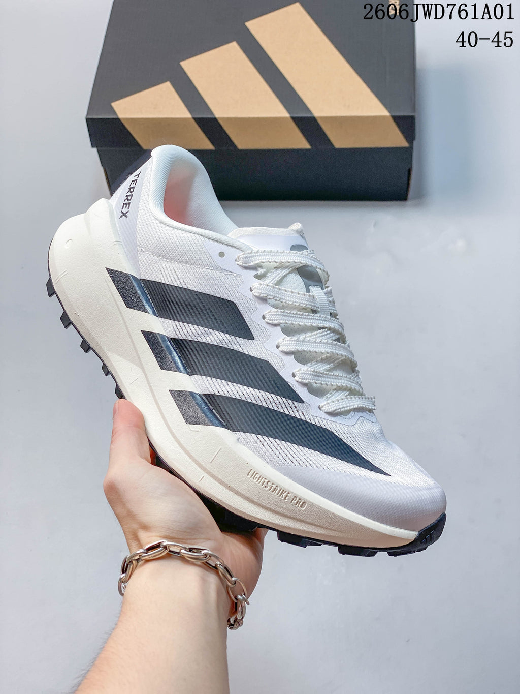 White Adidas Terrex trail running shoe with black stripes and a lugged outsole