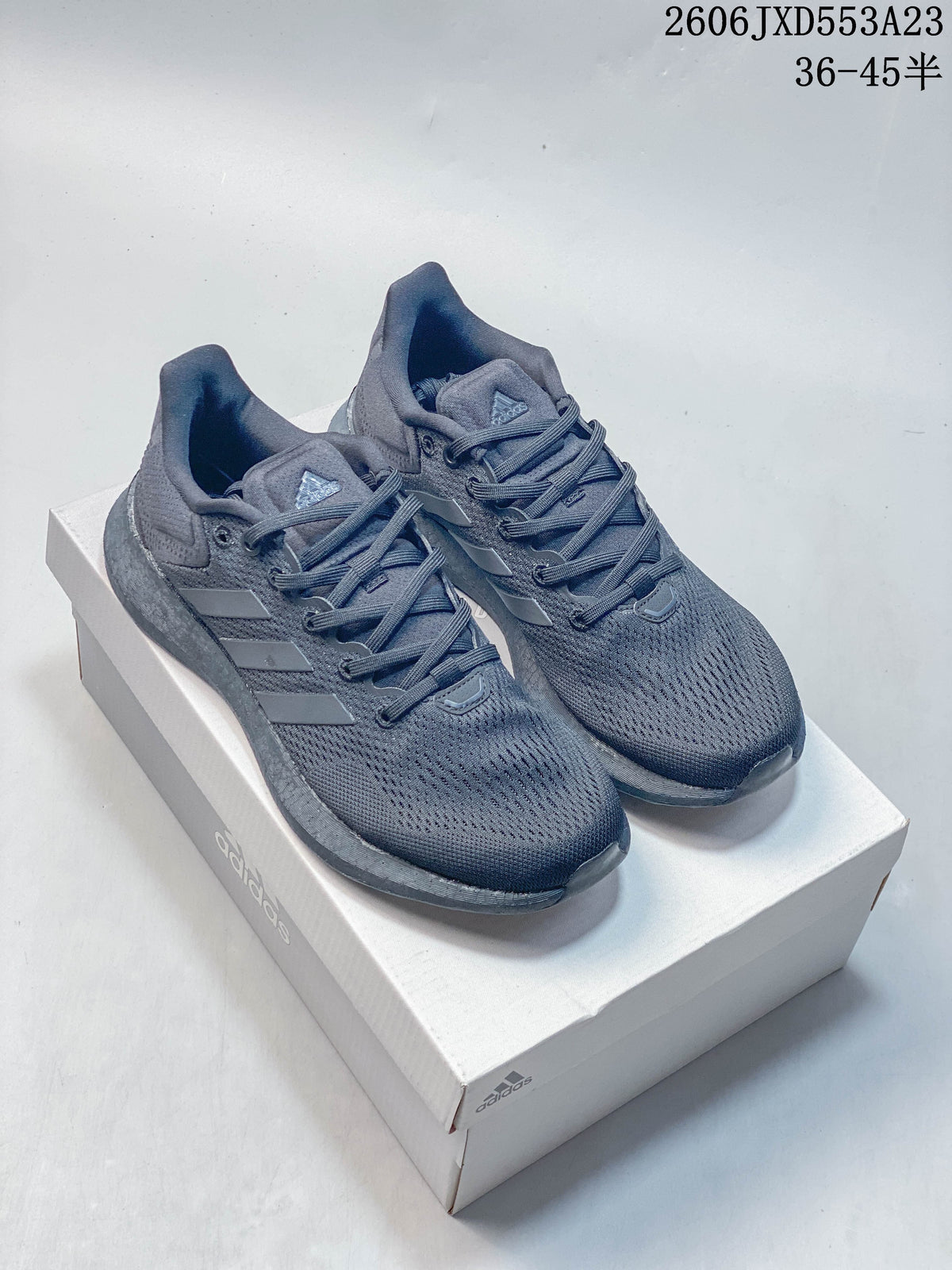 Pair of charcoal Adidas PureBoost 21 running shoes displayed on a shoebox.