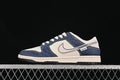 Side view of a cream and navy Nike SB Dunk Low with a repeating wordmark pattern on the overlays.