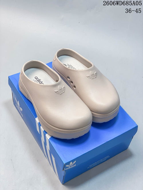 Pair of light beige adidas AdiFOM Stan Smith Mule clogs shown on a blue box.