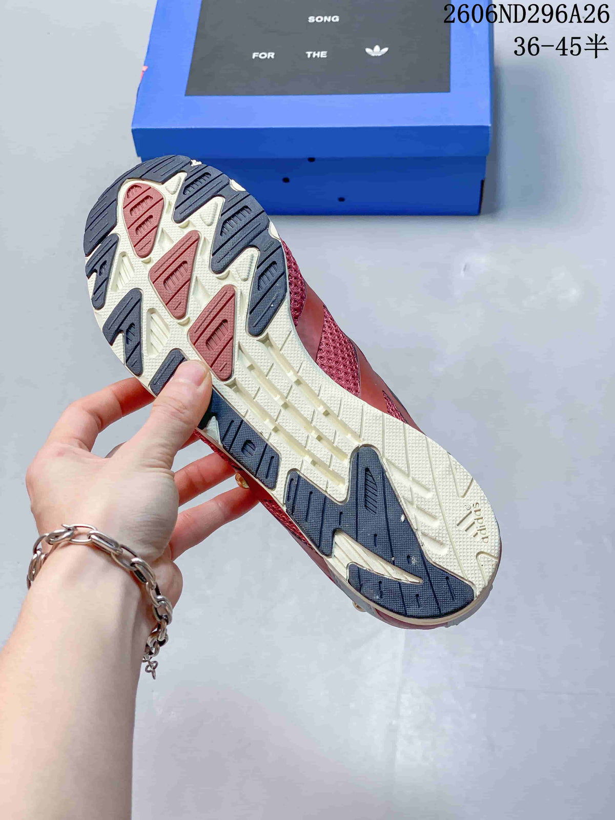 Underside of a sneaker showing a cream outsole with dark and red sections