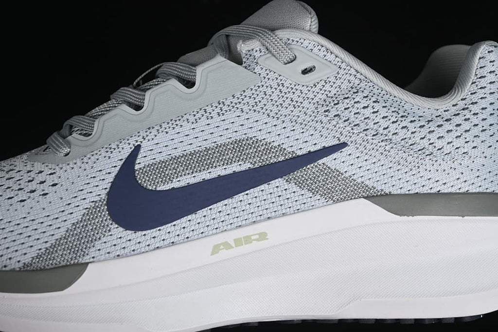 Side close-up showing patterned upper, navy Swoosh, gray accents, and white midsole
